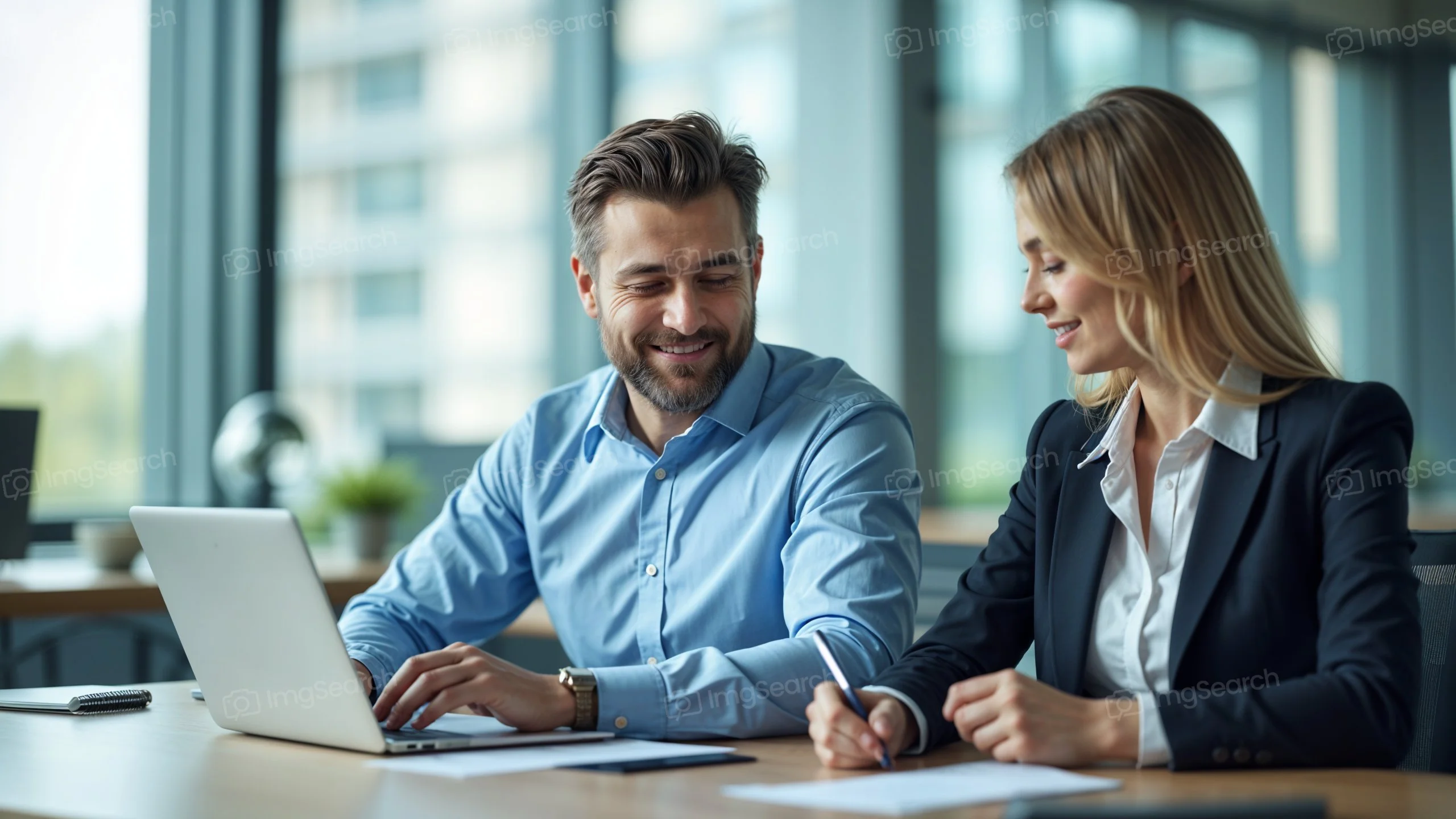Two professionals discussing over a laptop in a modern office environment